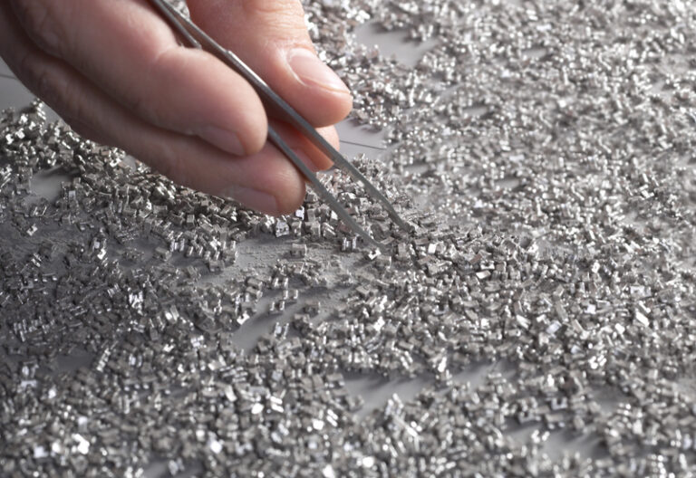Hand picking up small metal pieces with tweezers